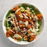 buffalo chicken strips on top of a salad in a bowl