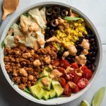 turkey salad in a bowl topped with corn, avocado, tomato, black olive, tortilla chips