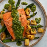 Pistachio pesto topped salmon with white sweet potatoes and asparagus on a plate