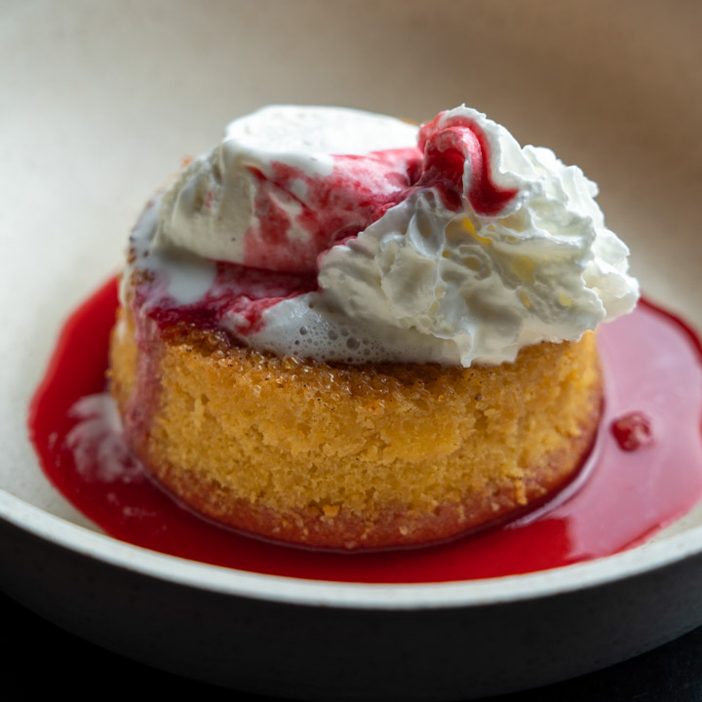 Butter cake with raspberry sauce and ice cream in a bowl
