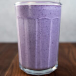 Blueberry Cheesecake Smoothie on a wooden table in a glass cup.