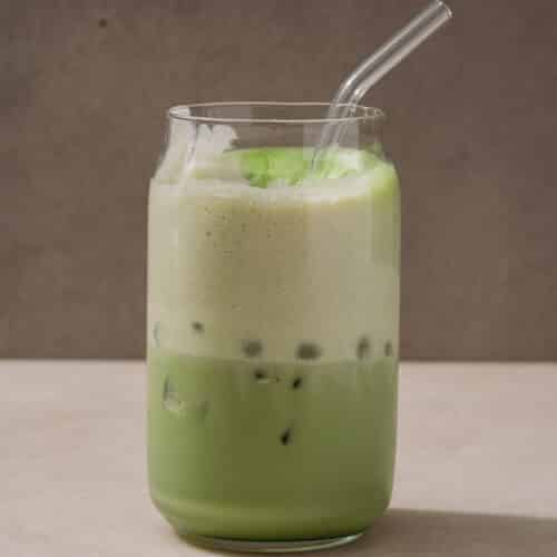 Iced Matcha Latte with Vanilla Cold Foam in a Glass Cup with a Glass Straw